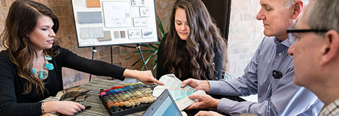 After receiving Lean learning for designers, four designers seated at a table coordinate on color for their design.