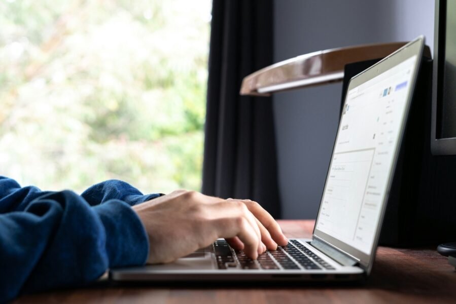 Person typing on a laptop at a wooden desk